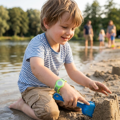 Kind baut Sandburg am See, neongrünes AirTag-Kinderarmband am Handgelenk
